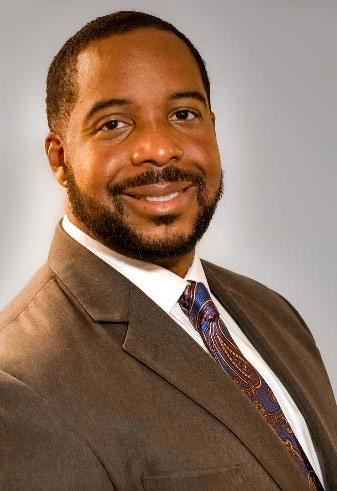 Dr. Terry Frazier is wearing a brown suit and multi-colored tie